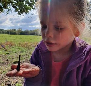 A little girl holding her hand out flat with a beautiful buterfly on it.